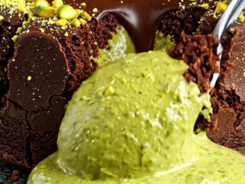 Dark chocolate lava cake sliced open with bright green pistachio ganache flowing out.