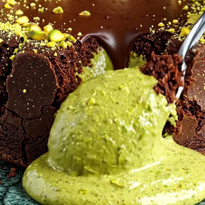Dark chocolate lava cake sliced open with bright green pistachio ganache flowing out.