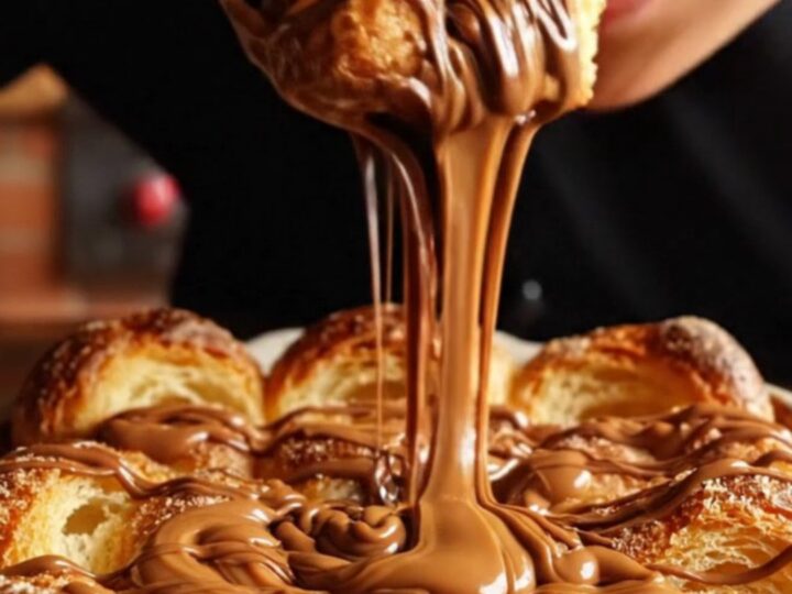 A golden-brown churro brioche bread pudding in a rustic dish with molten chocolate and caramel oozing out.