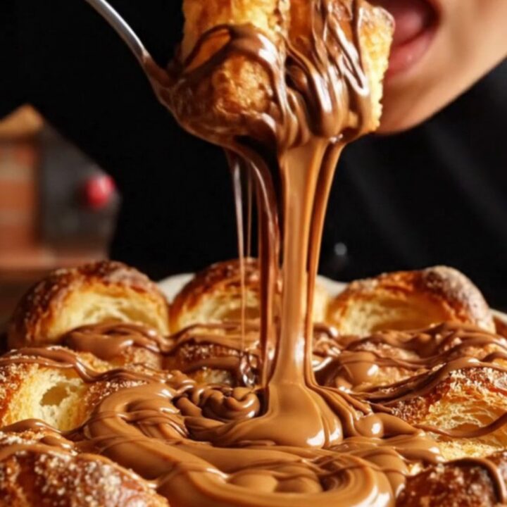 A golden-brown churro brioche bread pudding in a rustic dish with molten chocolate and caramel oozing out.