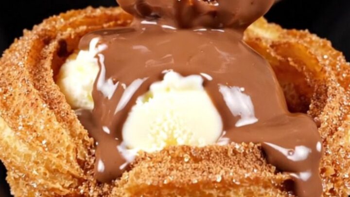 A close-up shot of a crispy golden churro bowl filled with vanilla ice cream and drizzled with rich Mexican chocolate sauce.