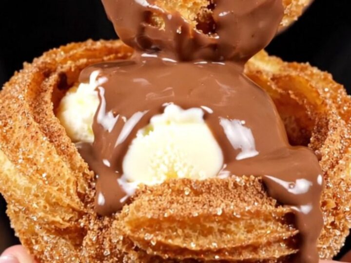 A close-up shot of a crispy golden churro bowl filled with vanilla ice cream and drizzled with rich Mexican chocolate sauce.