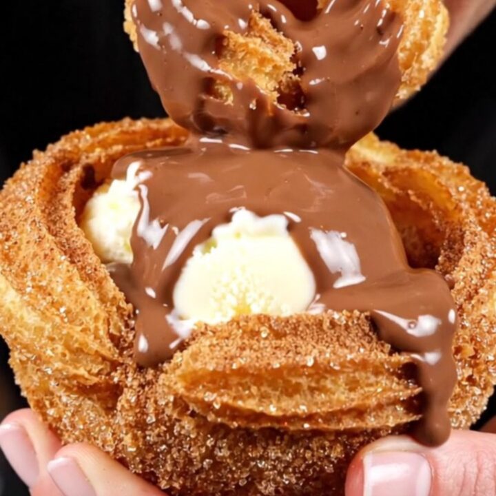 A close-up shot of a crispy golden churro bowl filled with vanilla ice cream and drizzled with rich Mexican chocolate sauce.