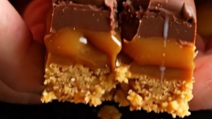 A close-up of a stack of three-layer Millionaire's shortbread squares with gold leaf garnish.