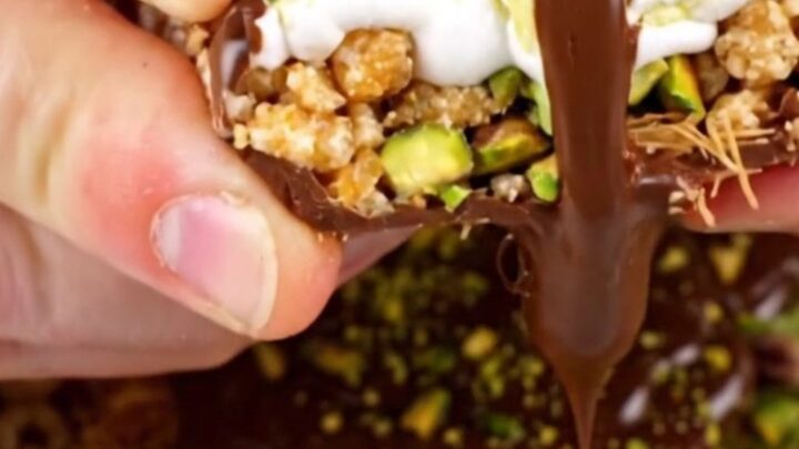 A close-up shot of a square of pistachio rice krispie treat being pulled apart, showing gooey marshmallow and crunchy layers.