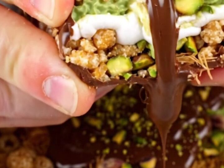 A close-up shot of a square of pistachio rice krispie treat being pulled apart, showing gooey marshmallow and crunchy layers.