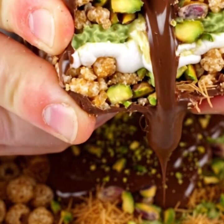 A close-up shot of a square of pistachio rice krispie treat being pulled apart, showing gooey marshmallow and crunchy layers.