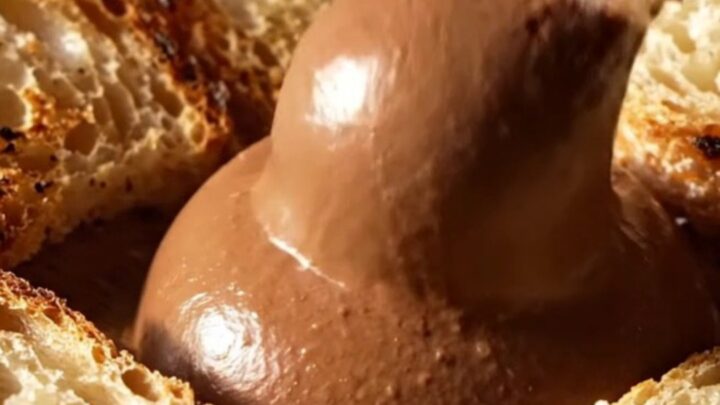 A close-up of dark chocolate mousse drizzled with olive oil and topped with flaky sea salt.