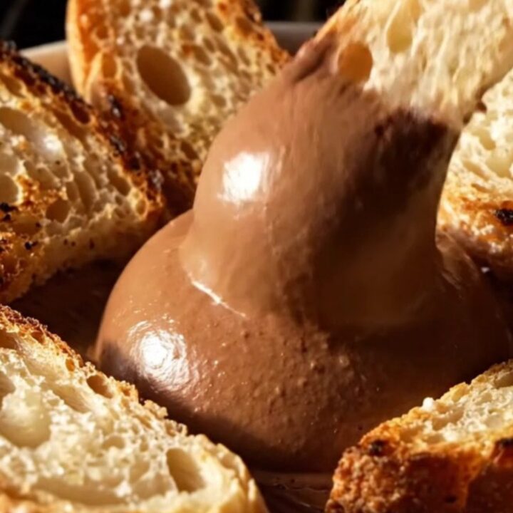 A close-up of dark chocolate mousse drizzled with olive oil and topped with flaky sea salt.
