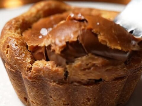 Extreme close-up of a chocolate tartlet sliced in half, revealing a flowing molten caramel and chocolate center.