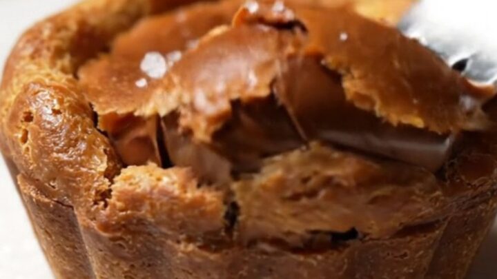 Extreme close-up of a chocolate tartlet sliced in half, revealing a flowing molten caramel and chocolate center.