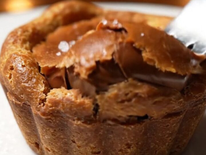Extreme close-up of a chocolate tartlet sliced in half, revealing a flowing molten caramel and chocolate center.