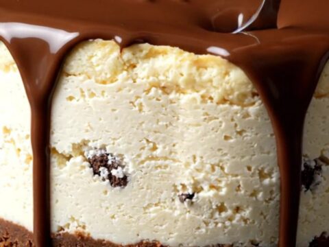 A towering cookies and cream cheesecake with a dark chocolate ganache drizzle and whipped cream rosettes.