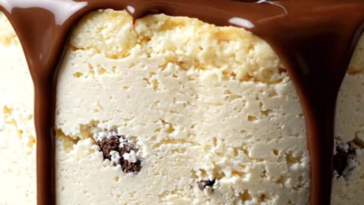 A towering cookies and cream cheesecake with a dark chocolate ganache drizzle and whipped cream rosettes.