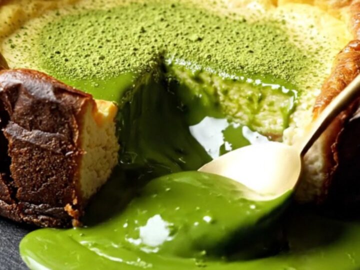 A close-up of a molten Uji matcha Basque cheesecake with a deeply charred top and a flowing emerald center.