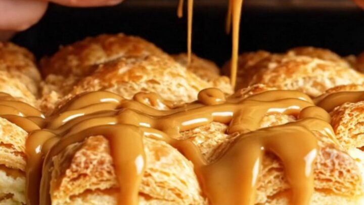 A close-up of a golden, crispy churro cheesecake square with a creamy center and a drizzle of dulce de leche.
