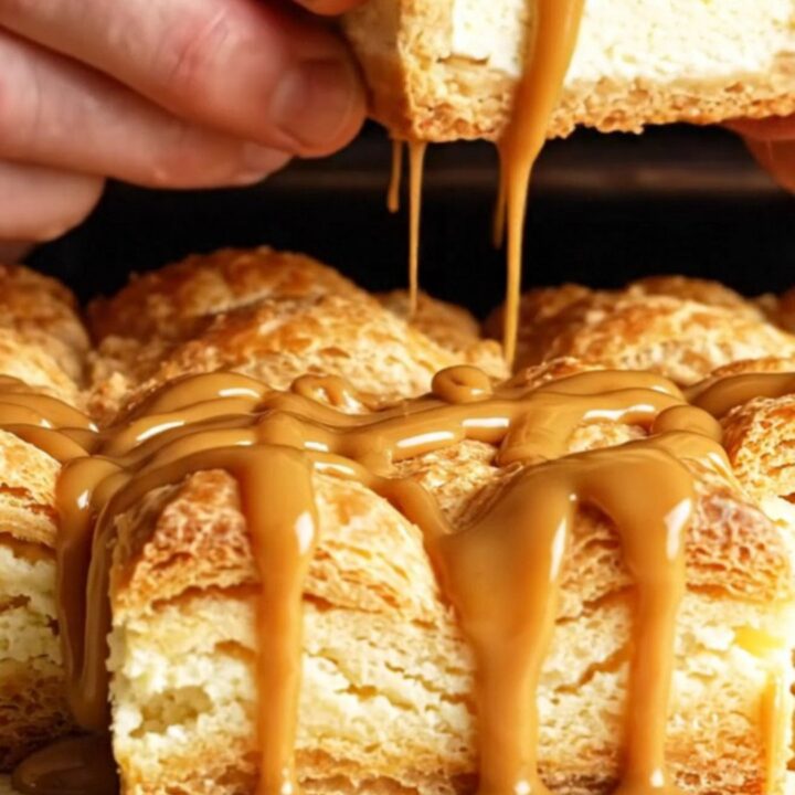 A close-up of a golden, crispy churro cheesecake square with a creamy center and a drizzle of dulce de leche.