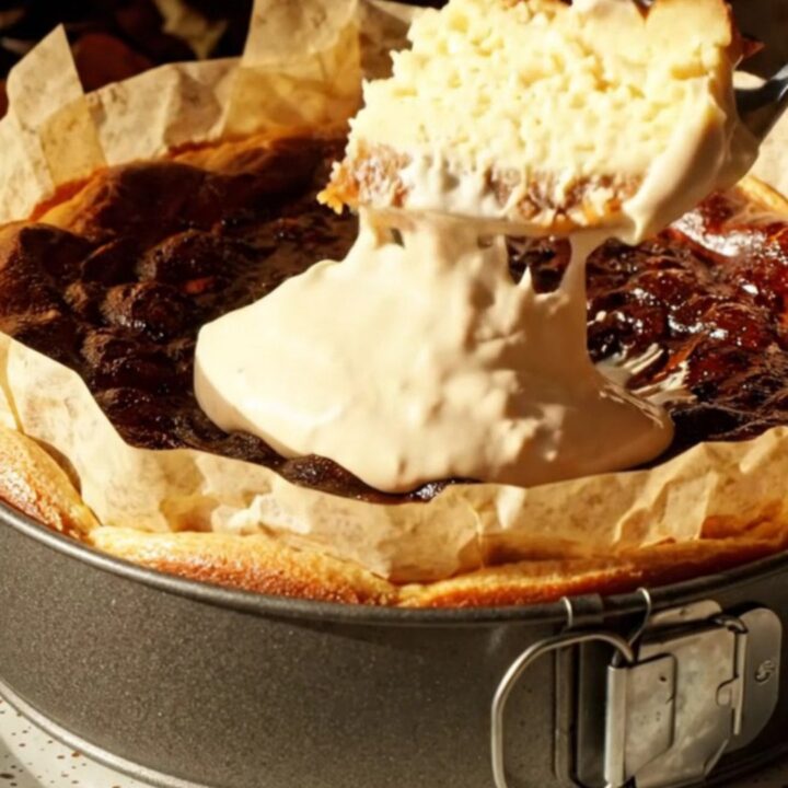A slice of golden-brown pumpkin Basque cheesecake on a vintage ceramic plate with a dollop of cream.