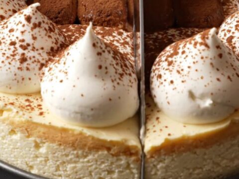A tall, elegant tiramisu cheesecake topped with mascarpone peaks and a dusting of dark cocoa powder.