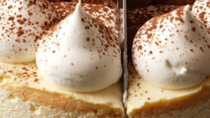 A tall, elegant tiramisu cheesecake topped with mascarpone peaks and a dusting of dark cocoa powder.