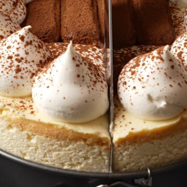 A tall, elegant tiramisu cheesecake topped with mascarpone peaks and a dusting of dark cocoa powder.