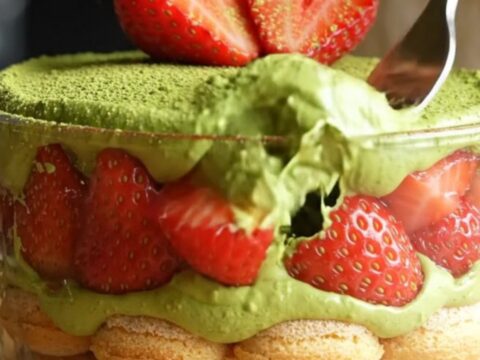 A vibrant Strawberry Matcha Tiramisu with green cream and red berries in a square glass dish.