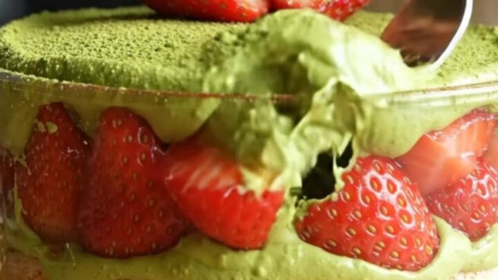 A vibrant Strawberry Matcha Tiramisu with green cream and red berries in a square glass dish.