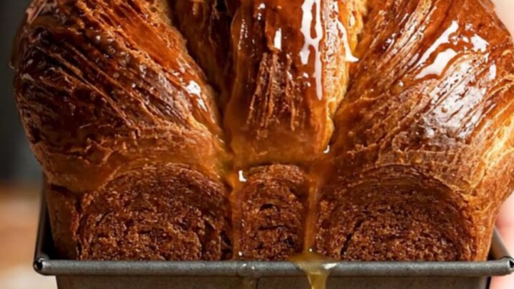 A sliced chocolate laminated brioche loaf showing distinct, flaky layers and a rich mahogany crust.