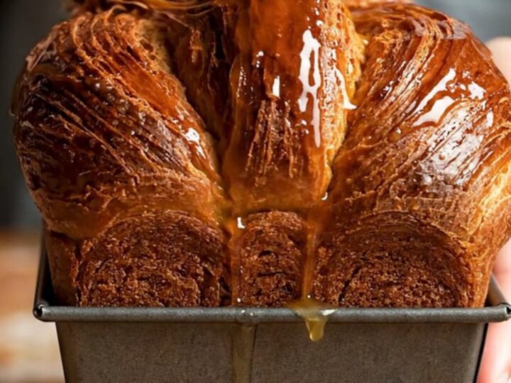 A sliced chocolate laminated brioche loaf showing distinct, flaky layers and a rich mahogany crust.