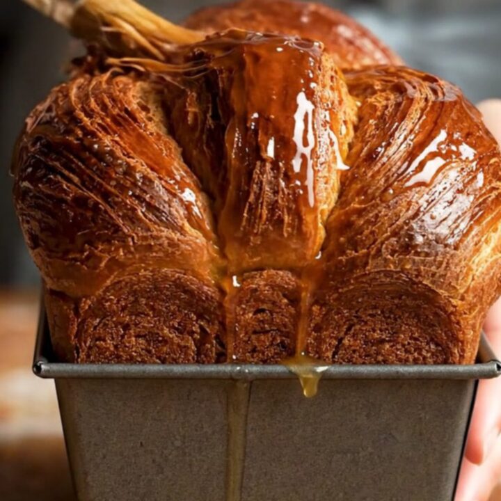 A sliced chocolate laminated brioche loaf showing distinct, flaky layers and a rich mahogany crust.