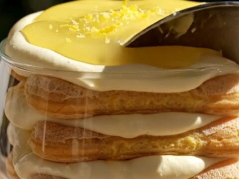 A close-up of a spoonful of creamy Lemon Limoncello Tiramisu with glossy lemon curd swirls and candied lemon zest.