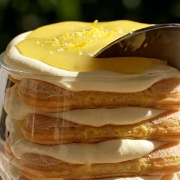 A close-up of a spoonful of creamy Lemon Limoncello Tiramisu with glossy lemon curd swirls and candied lemon zest.