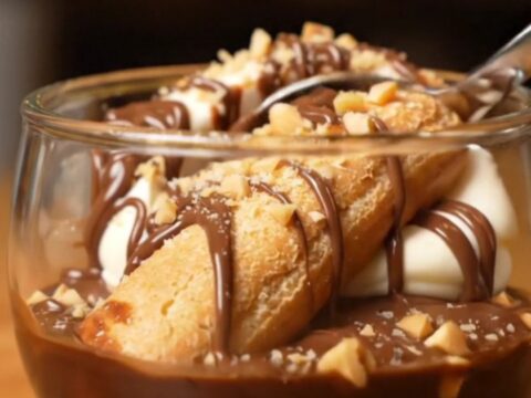 A close-up shot of a creamy Nutella tiramisu with hazelnut garnish in a glass dish.