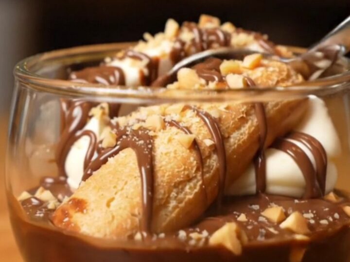 A close-up shot of a creamy Nutella tiramisu with hazelnut garnish in a glass dish.