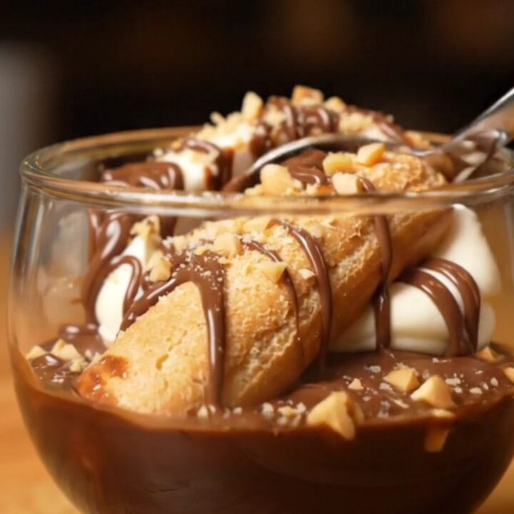 A close-up shot of a creamy Nutella tiramisu with hazelnut garnish in a glass dish.