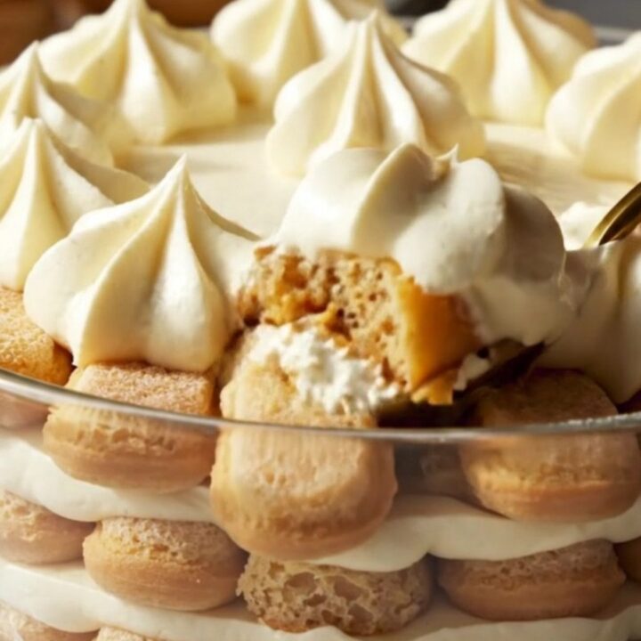 A glass dish filled with layers of Earl Grey lavender tiramisu, topped with elegant piping and a dusting of lavender buds.
