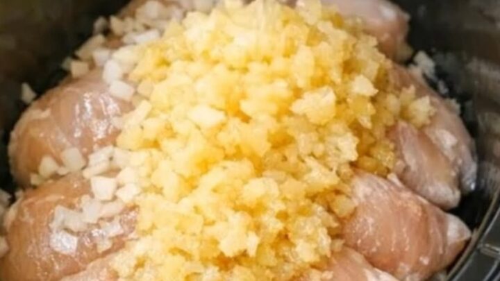 A close-up shot of tender shredded chicken coated in a glistening, sweet golden pineapple glaze in a slow cooker.