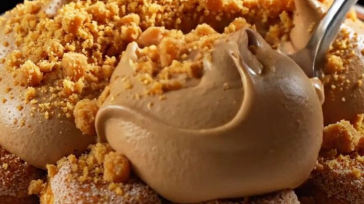 A close-up of a square of pumpkin spice chai latte tiramisu with piped mascarpone peaks and cookie crumbs.