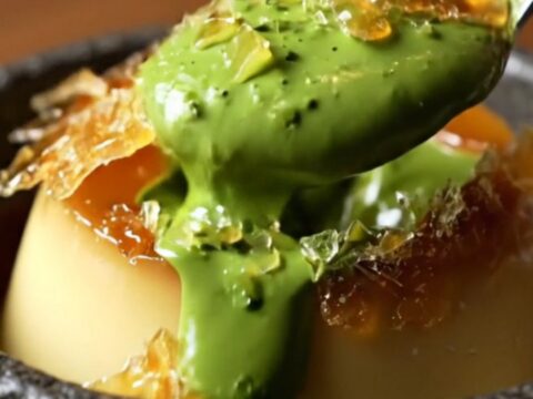 A close-up of a jade-green matcha crème brûlée with a shattered amber sugar crust.