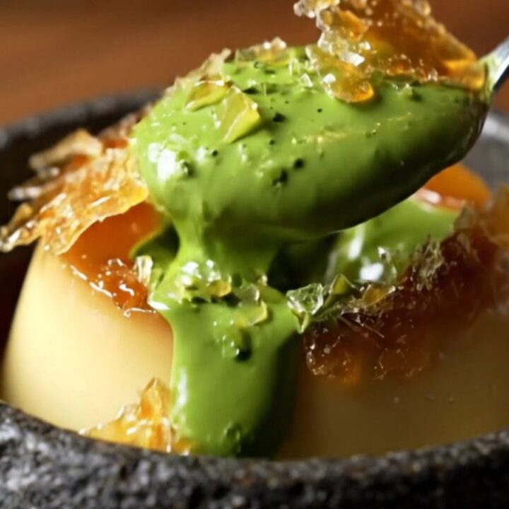 A close-up of a jade-green matcha crème brûlée with a shattered amber sugar crust.