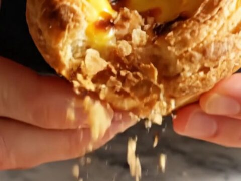 A close-up shot of a freshly baked Portuguese Pastel de Nata with a perfectly blistered, caramelized custard top.