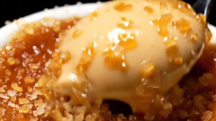A close-up shot of a spoon cracking the dark, caramelized sugar crust of an espresso crème brûlée.