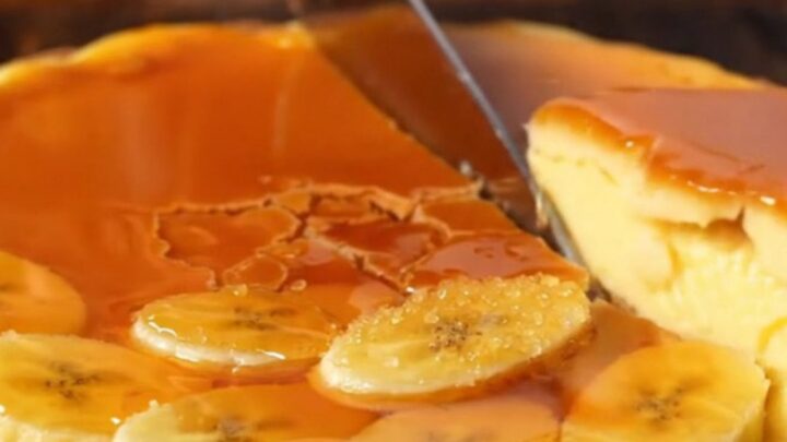 A close-up of a torched banana custard tart with a golden, crackling caramelized top and a crisp pastry crust.