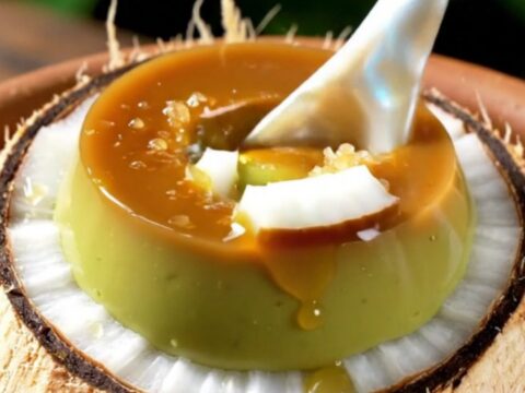 A close-up shot of a creamy green pandan crème brûlée inside a coconut shell with a caramelized sugar crust.