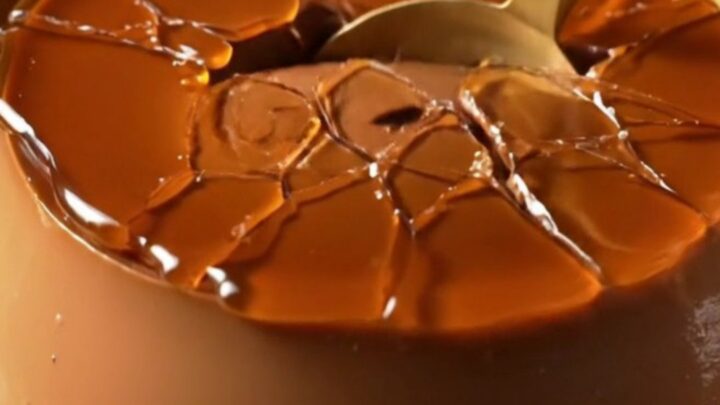 A dark chocolate crème brûlée with a golden, shattered caramelized sugar crust in a ceramic ramekin.