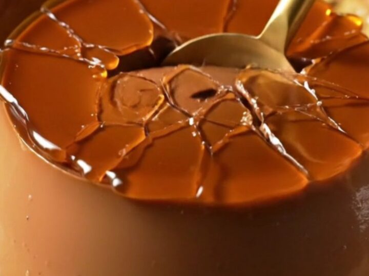 A dark chocolate crème brûlée with a golden, shattered caramelized sugar crust in a ceramic ramekin.
