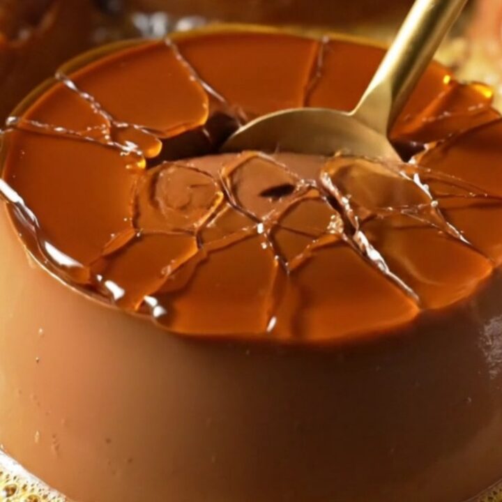 A dark chocolate crème brûlée with a golden, shattered caramelized sugar crust in a ceramic ramekin.