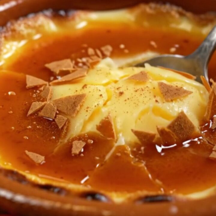 A close-up of a traditional Spanish Crema Catalana in a clay cazuela with a perfectly browned, burnt sugar crust.