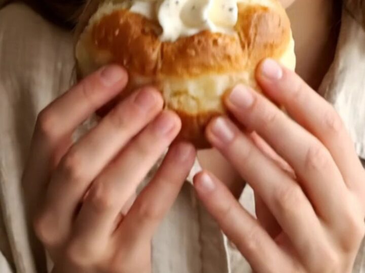 A close-up of a golden fried bomboloni being pulled apart, showing the creamy vanilla filling inside.