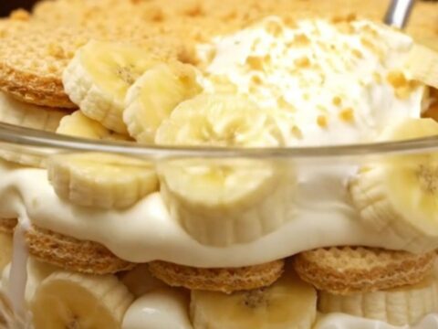 A large glass trifle bowl filled with layers of creamy vanilla pudding, fresh banana slices, and golden vanilla wafers.